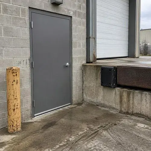 Gray steel single door in a steel frame on a concrete block industrial building