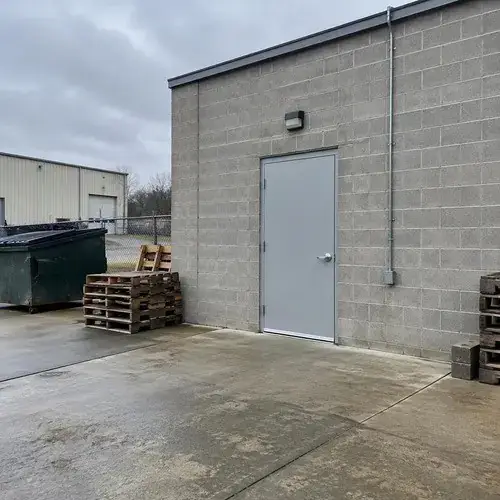 Grey steel personnel door in steel frame on a concrete block industrial building with