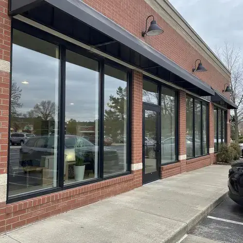 Black-framed storefront windows and glass entrance door on a red brick commercial building with