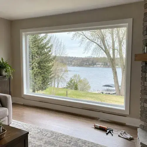 Oversized white-framed picture window in a living room with lake view