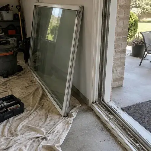 Sliding glass door panel removed and leaning on drop cloth