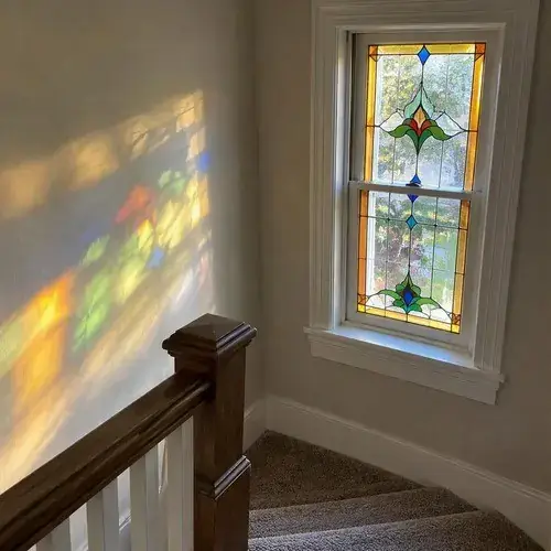 Double-hung window with colourful stained glass floral design in a stairwell