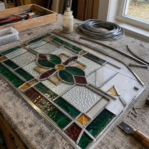 Partially assembled leaded stained glass panel with floral design on a workbench with lead