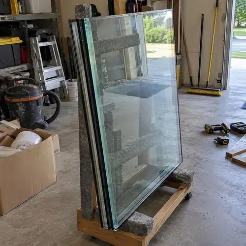 Stack of insulated glass units on a wooden cart in a garage with tools