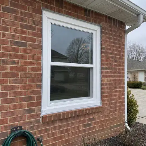 New white vinyl double-hung window in a red brick wall with brick sill
