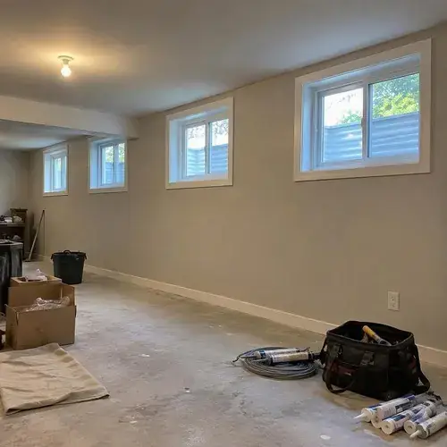 Unfinished basement with small white-framed windows along wall