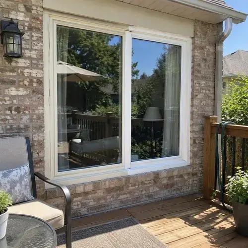 Large white-framed window with a fixed pane and casement on a brick home overlooking