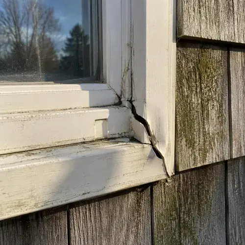 Close view of a white painted window frame and sill with a cracked