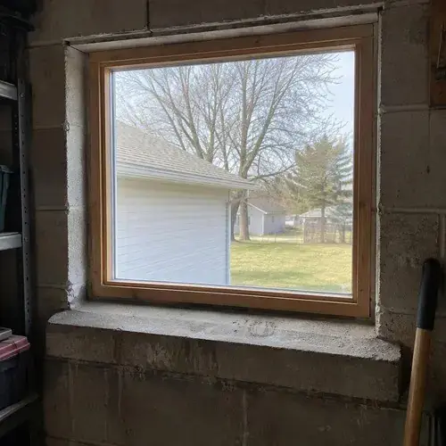 Wood-framed fixed window set in a concrete block wall of a basement or garage